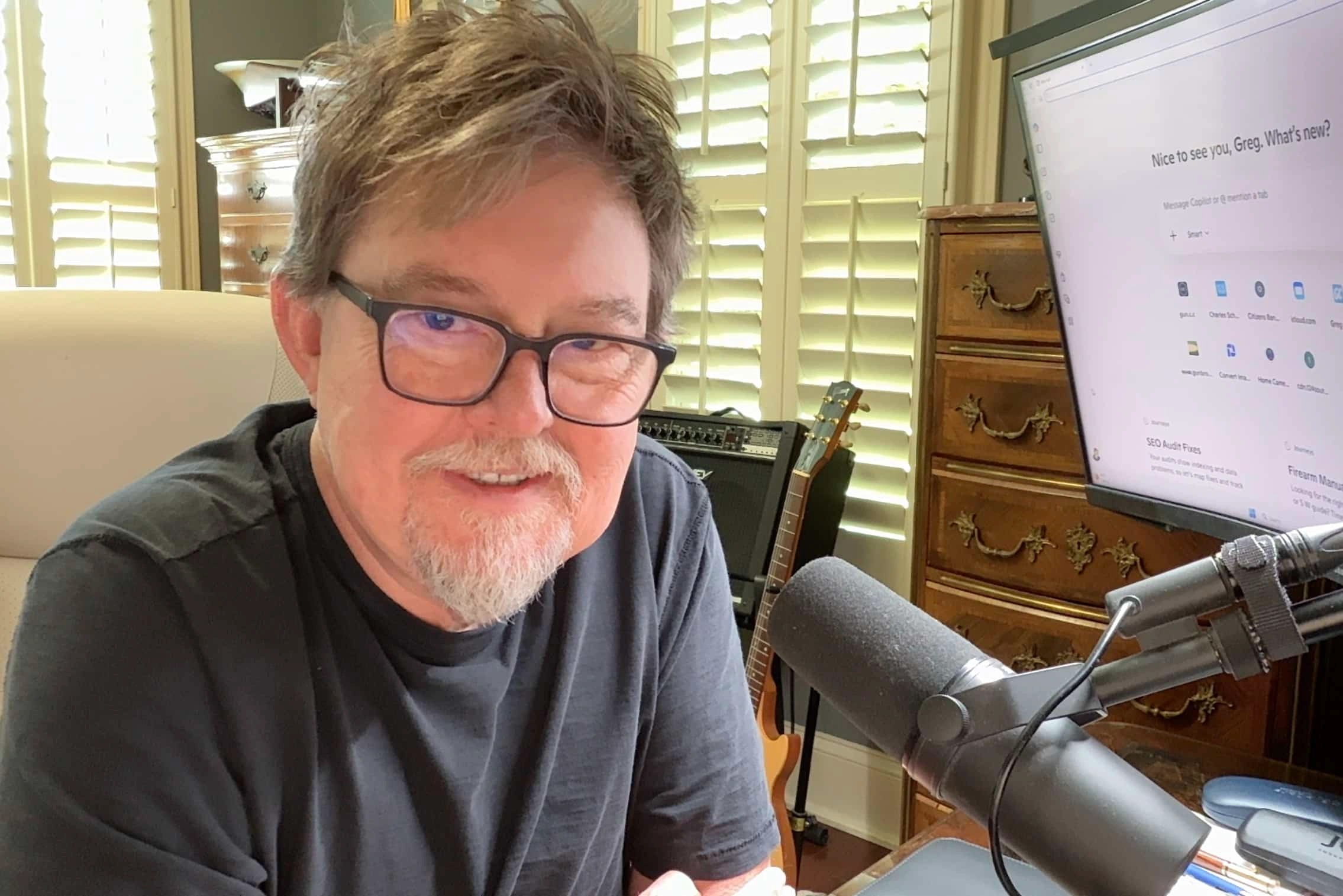 Greg Cook at his desk with his computer and microphone
