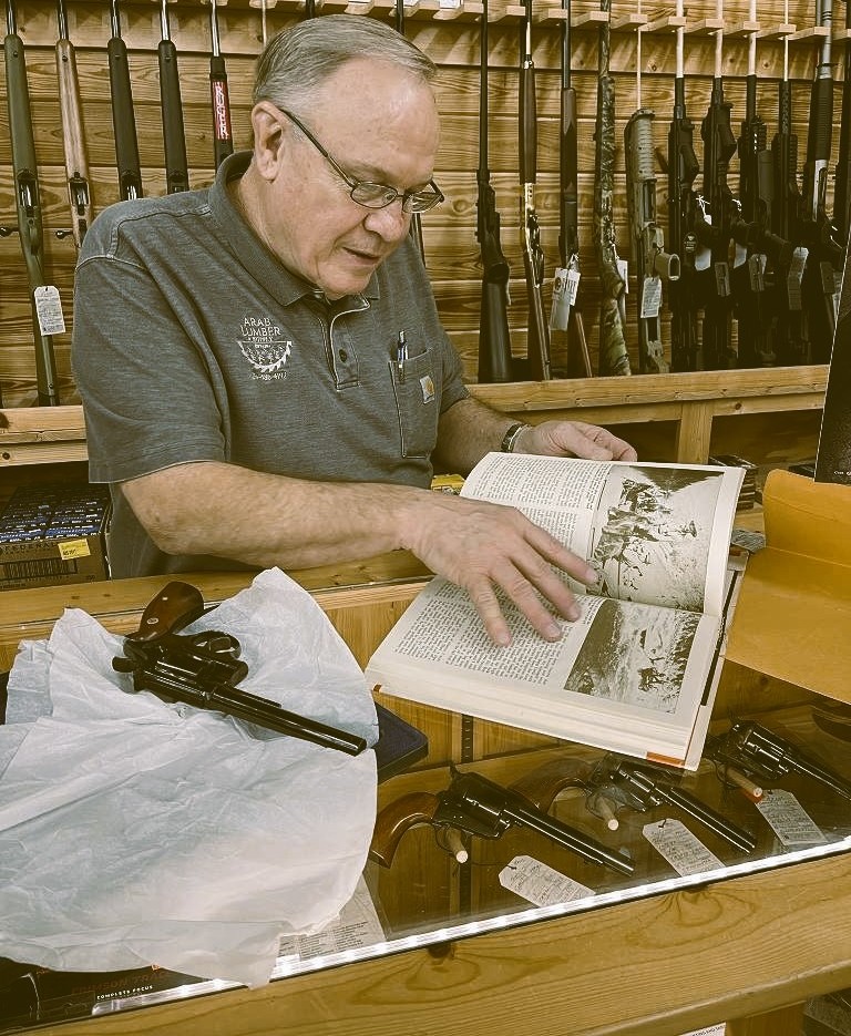 Collector reviewing firearm reference material at a gun counter