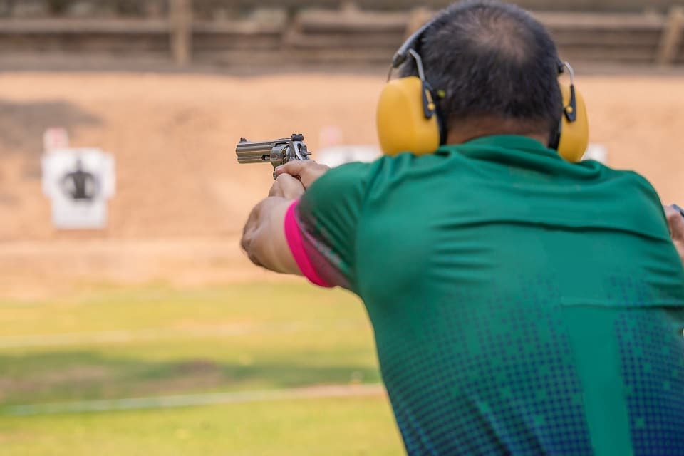 man firing handgun at gun range