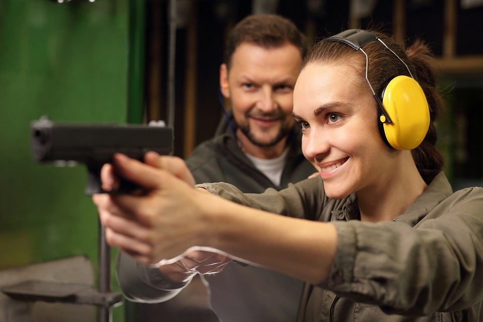 firearms instructor assisting a female trainee at the gun range