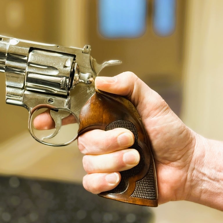 Shooter's Hand gripping a 1962 Colt Python wearing Ropers