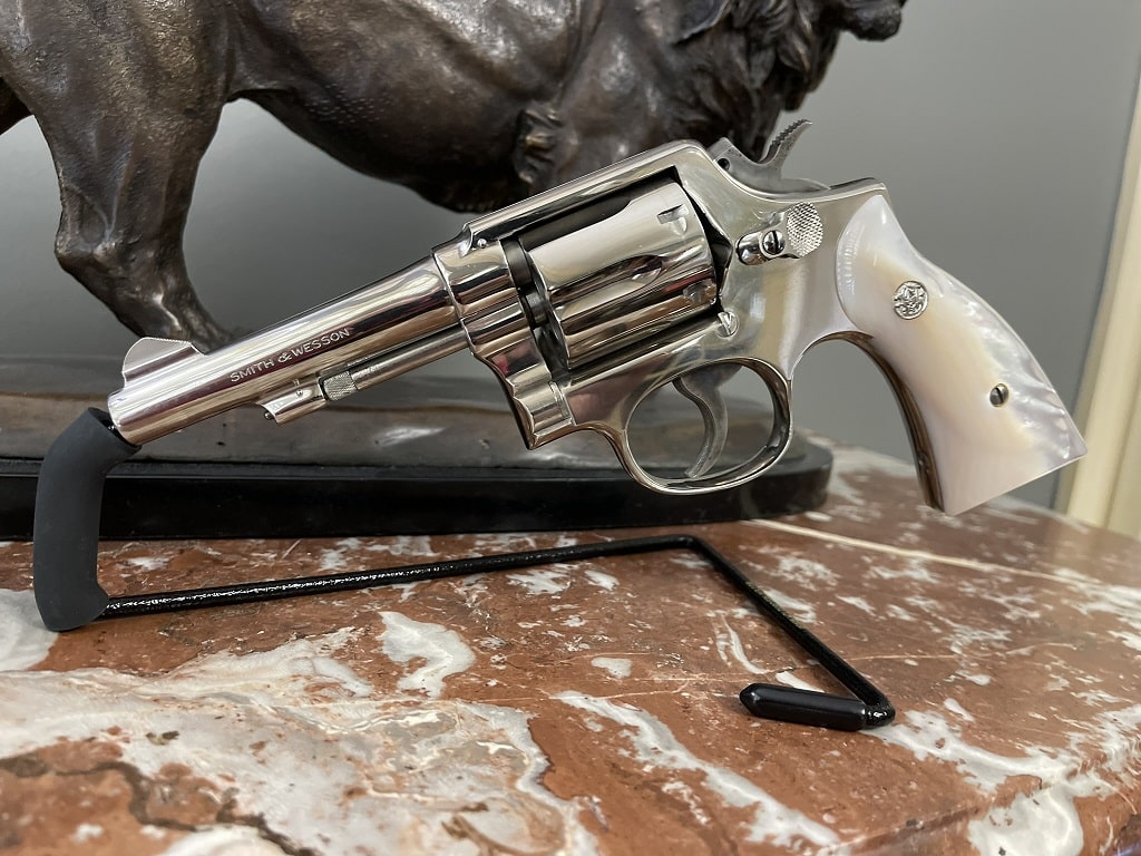 Nickel Smith & Wesson Model 10 style K-Frame revolver with pearl stocks, fixed sights, exposed hammer, and short barrel displayed on marble