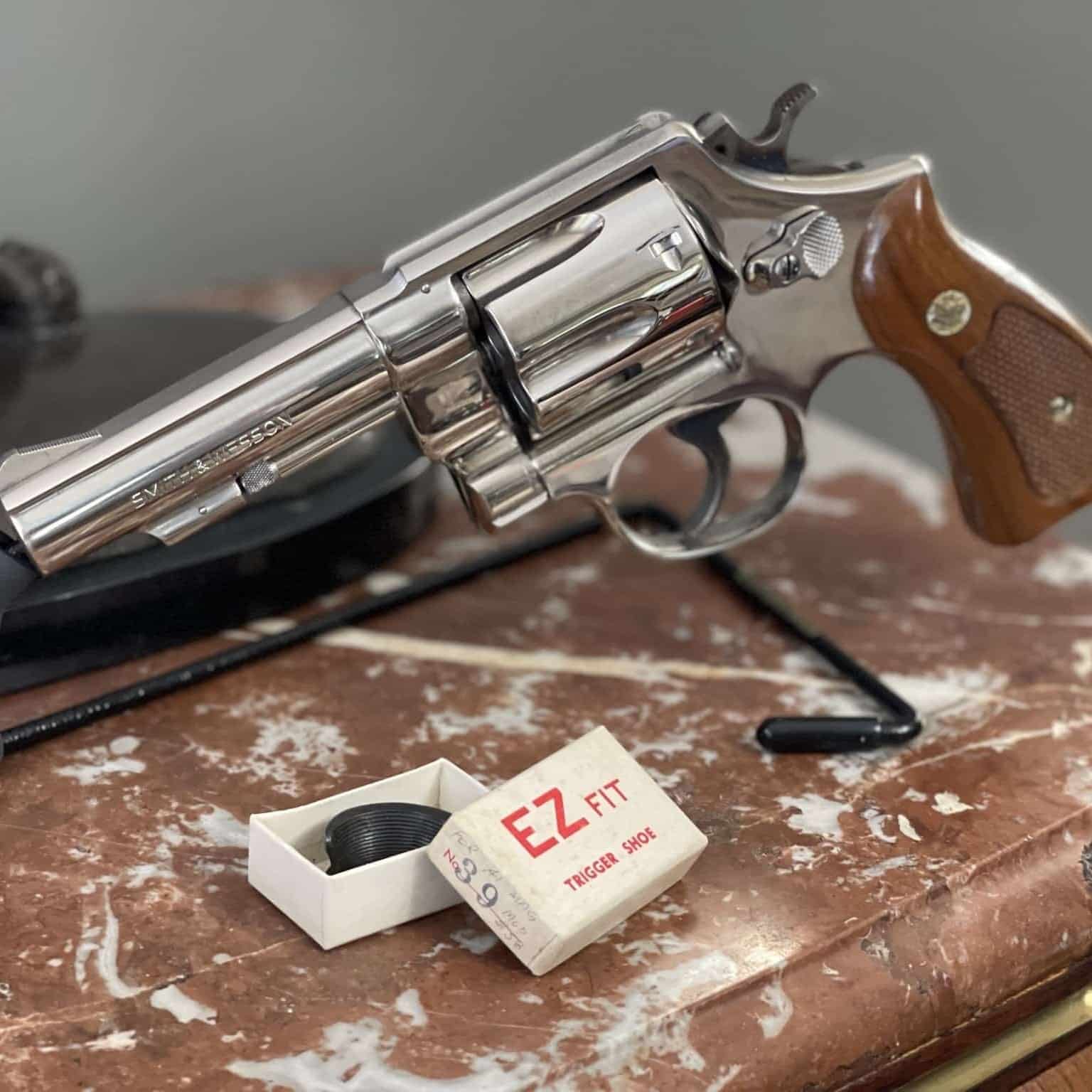 Nickel Smith & Wesson revolver with wood medallion stocks and EZ Fit trigger shoe packaging shown as Smith & Wesson model-era collector context