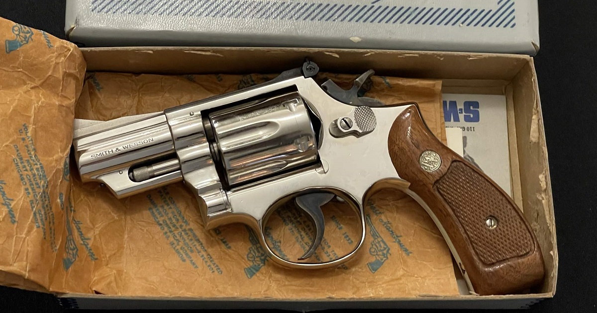 Stainless Smith & Wesson K-Frame revolver resting in its original box with factory papers and checkered walnut medallion stocks