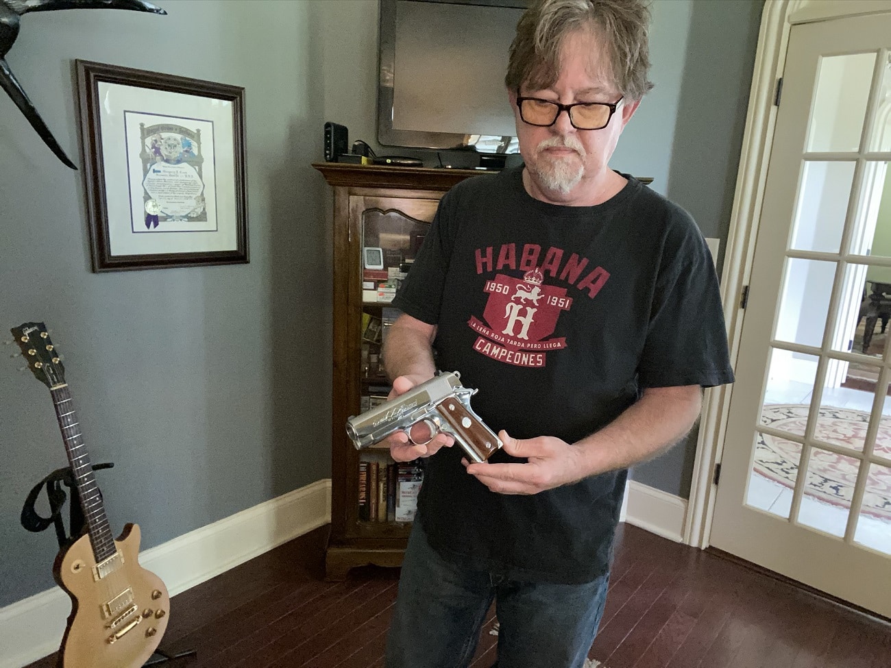Greg Cook examining a polished semi-automatic pistol