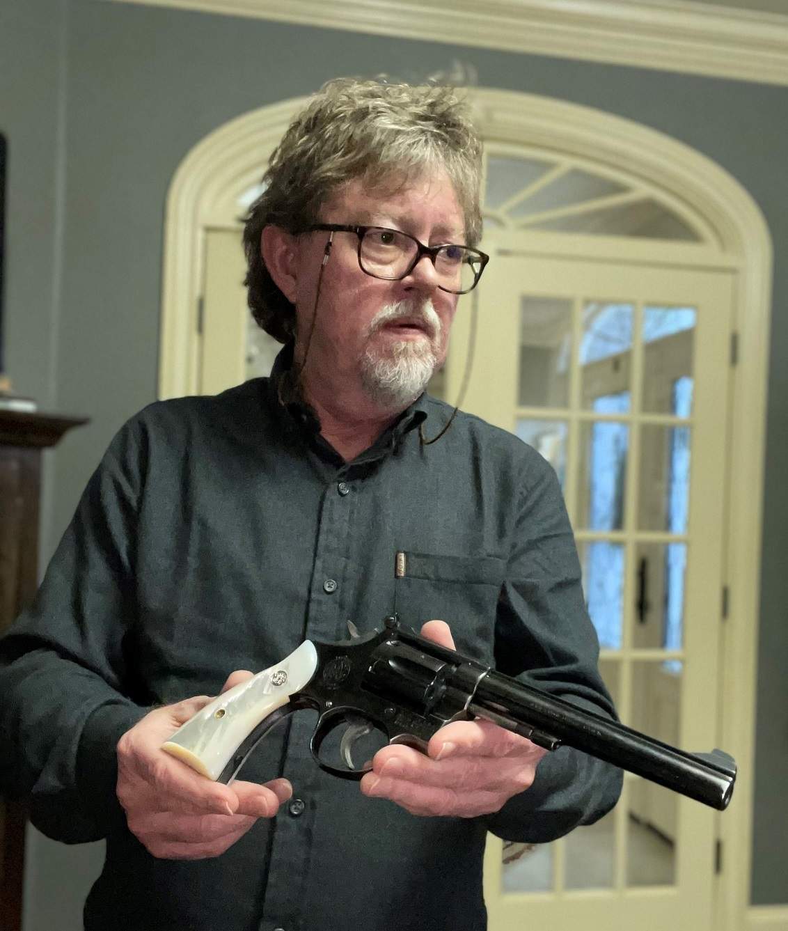 Greg Cook holding a long-barreled Smith and Wesson revolver with pearl grips