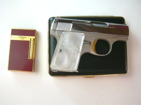 Browning .25 caliber pistol laying on a cigarette case next to st dupont lighter