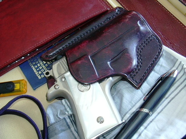 My Colt Mustang .380 in a pocket holster laying on my open open Italian leather brief portfolio